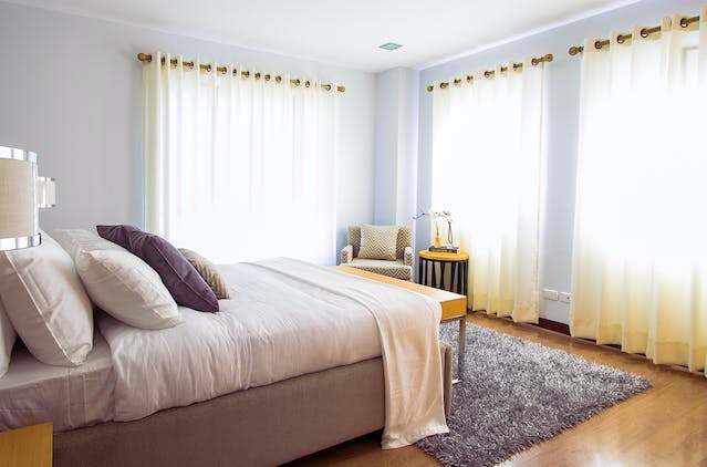a bedroom with large windows and hardwood flooring