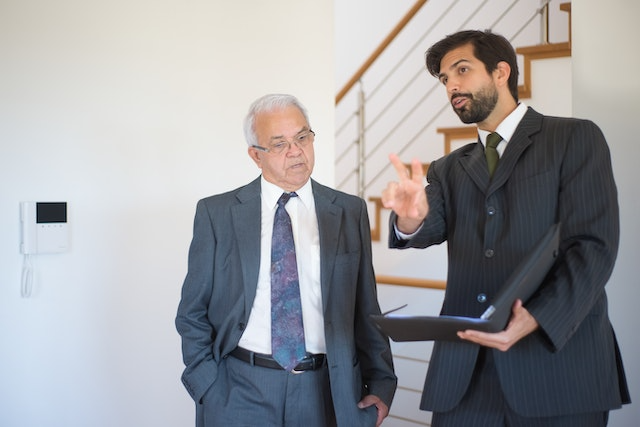 A landlord and property manager wearing suits looking at a property together
